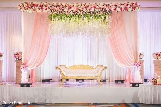 Baby pink drape with orchids hanging from the ceiling and a mixed floral border